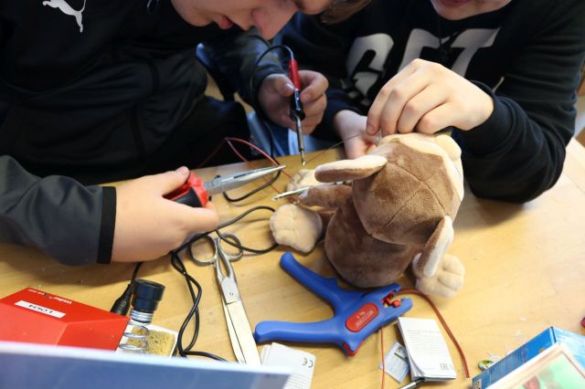 Zwei Schüler bearbeiten mit Zange und Lötkolben einen unschuldigen Affen. Pulp Fiction Referenz! Telefonstreich! Telefonstreich!